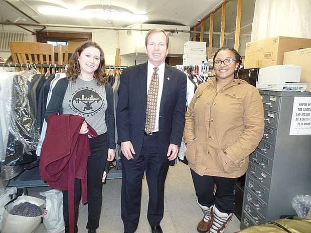 Bill O'Donnell and two women standing in front of a rack of clothes.